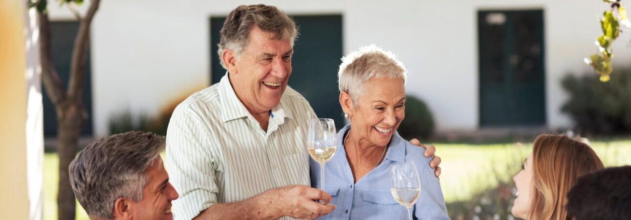 Happy senior couple with family having lunch together outside