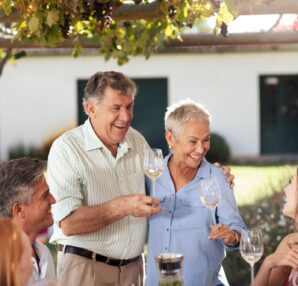 Happy senior couple with family having lunch together outside