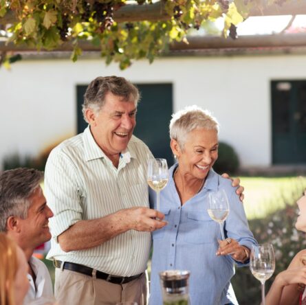Happy senior couple with family having lunch together outside
